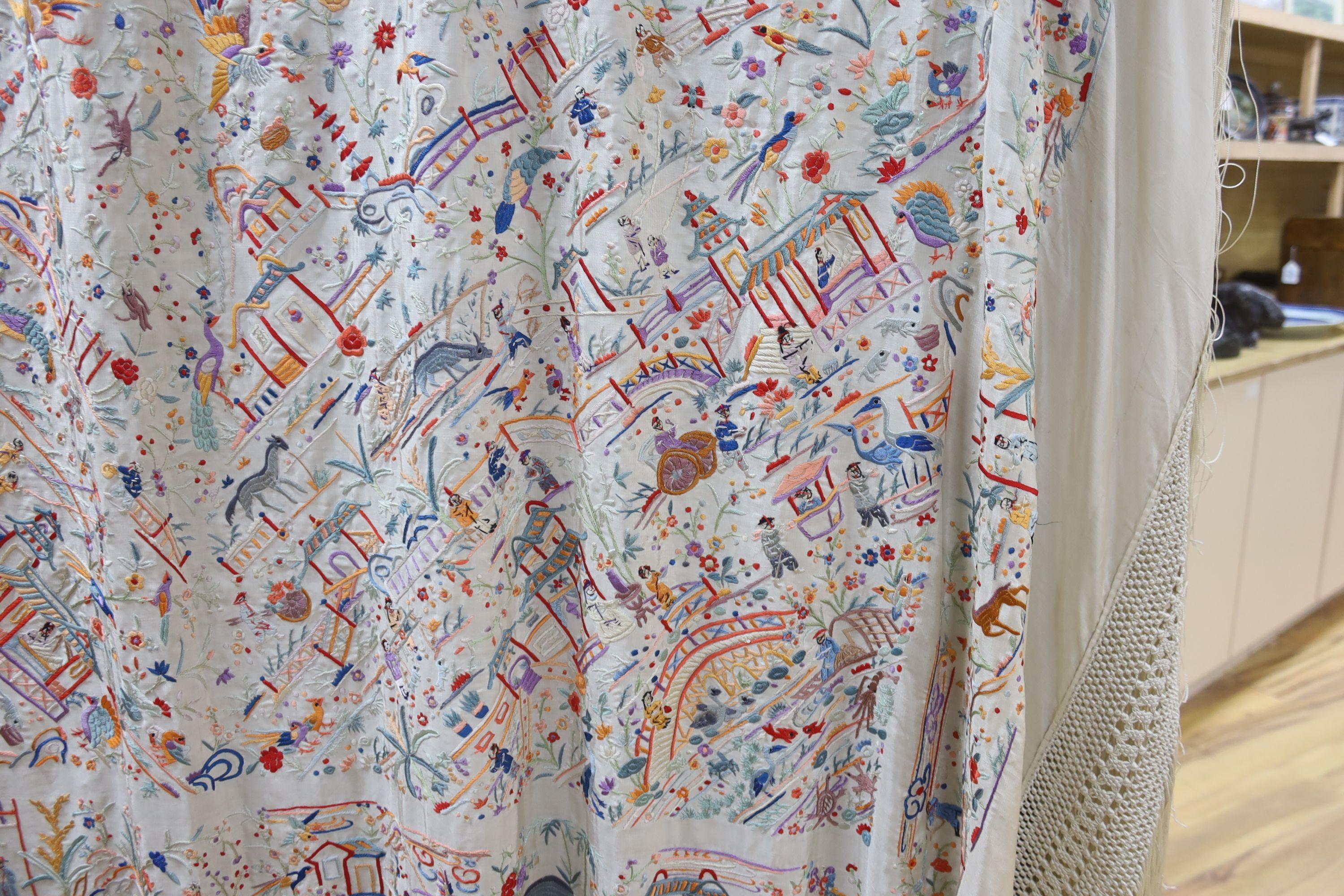 A Chinese cream silk shawl with fine multi coloured all over embroidery depicting figurative scenes and animals